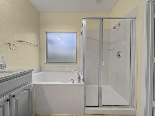 bathroom featuring vanity, a bath, a textured wall, and a stall shower