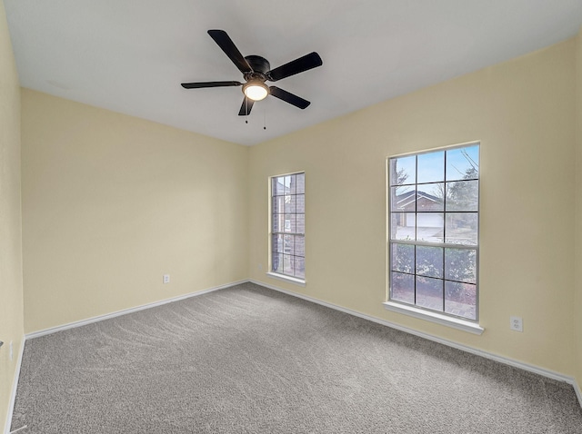 carpeted empty room featuring a ceiling fan and baseboards