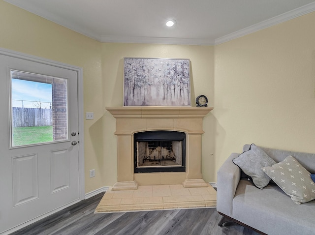 interior space with a fireplace with raised hearth, wood finished floors, baseboards, and ornamental molding