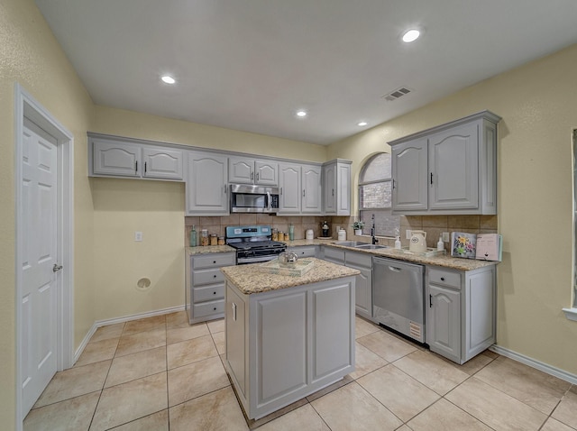 kitchen featuring visible vents, gray cabinetry, a sink, backsplash, and appliances with stainless steel finishes