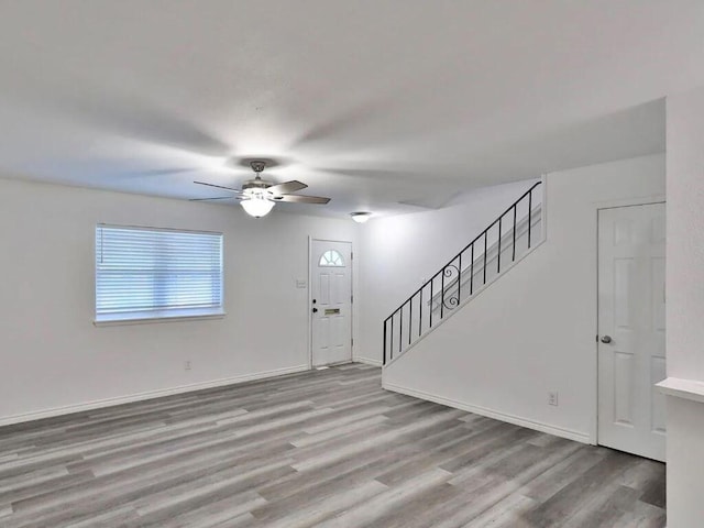 interior space with stairway, baseboards, wood finished floors, and a ceiling fan