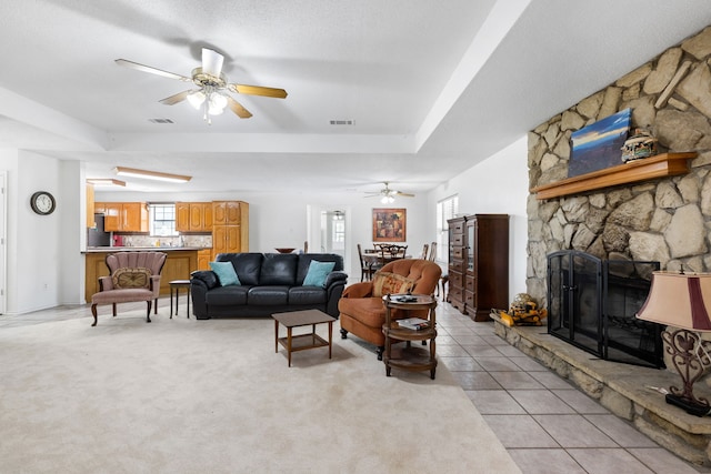 living area with a raised ceiling, light tile patterned flooring, a fireplace, and visible vents