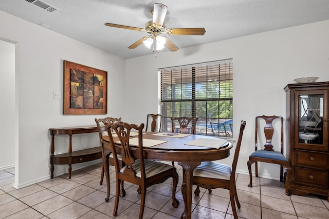 dining room featuring light tile patterned floors, a ceiling fan, visible vents, baseboards, and a textured ceiling