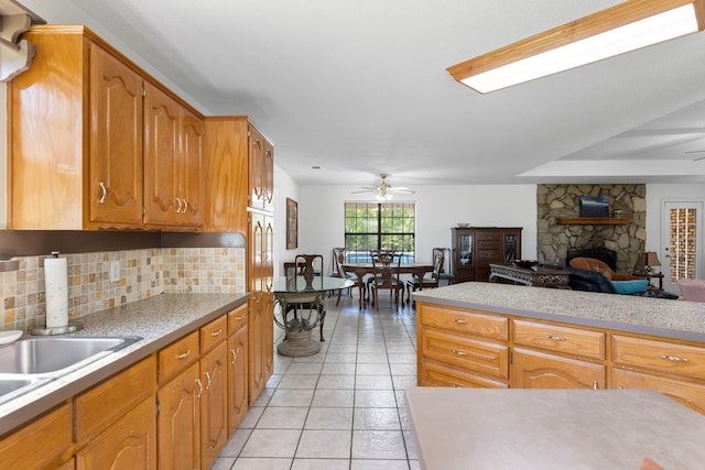 kitchen featuring light tile patterned floors, tasteful backsplash, a fireplace, and light countertops