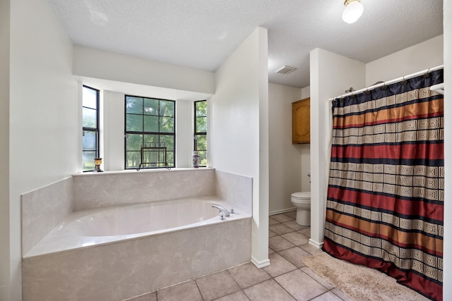 bathroom with tile patterned flooring, a textured ceiling, toilet, and a bath