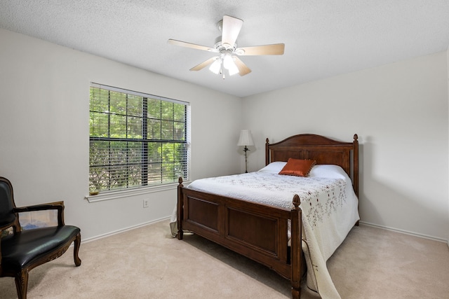 bedroom with a ceiling fan, light colored carpet, baseboards, and a textured ceiling