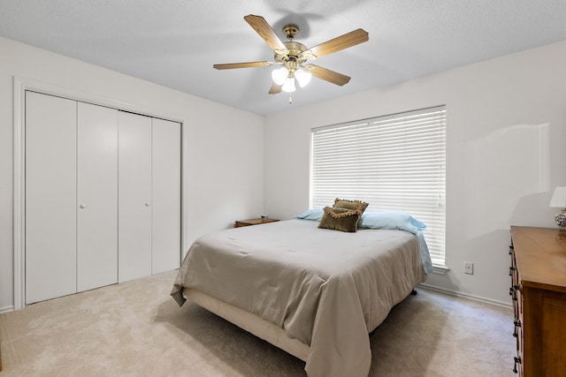 bedroom with light carpet, ceiling fan, and a closet