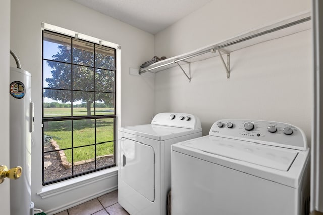 laundry room with light tile patterned floors, laundry area, washer and dryer, and water heater