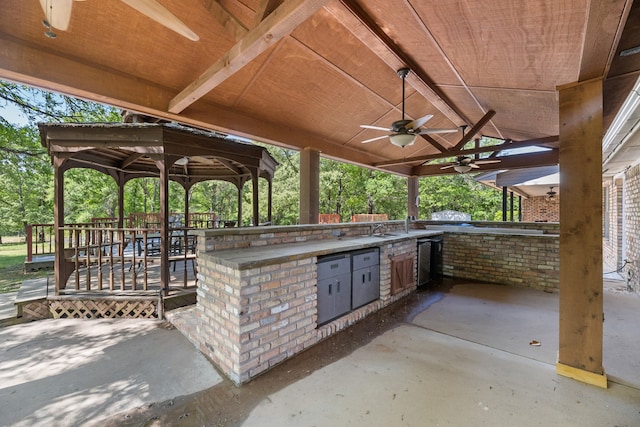 view of patio featuring an outdoor kitchen, a gazebo, a sink, and ceiling fan