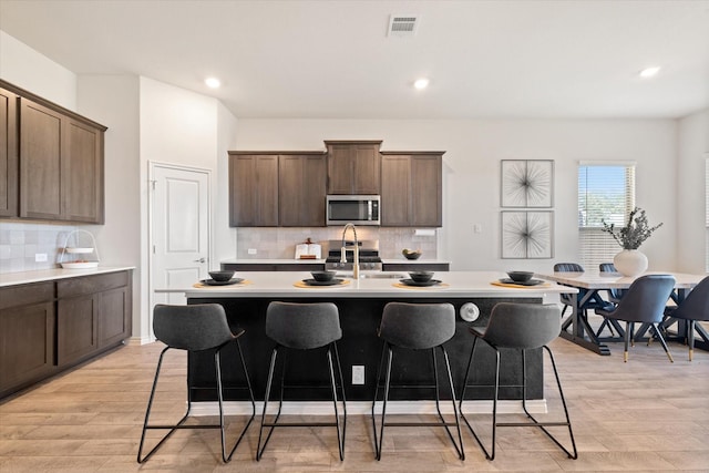 kitchen with stainless steel microwave, a kitchen breakfast bar, light countertops, and a sink