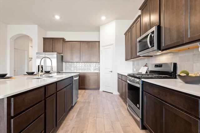 kitchen featuring light countertops, light wood-type flooring, appliances with stainless steel finishes, and a sink