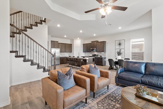 living area with recessed lighting, light wood-type flooring, stairs, and baseboards