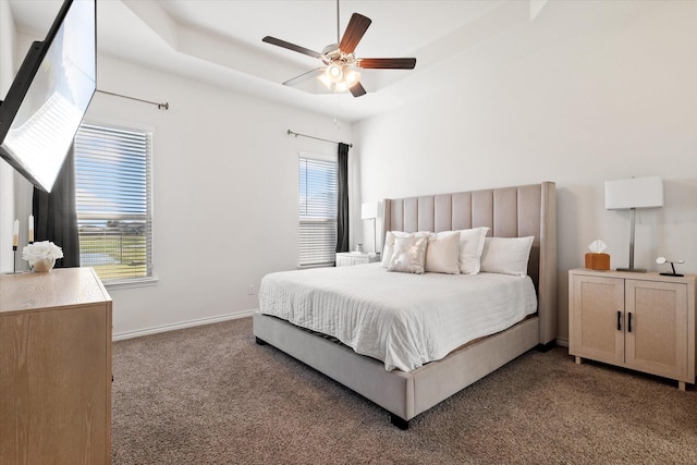 carpeted bedroom with a tray ceiling, baseboards, and ceiling fan