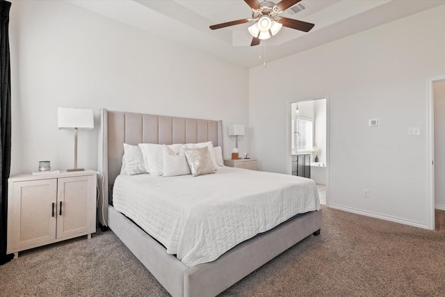 bedroom featuring baseboards, visible vents, ensuite bath, a raised ceiling, and light colored carpet