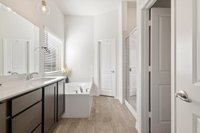 full bath featuring vanity, a shower stall, a bath, and wood finished floors