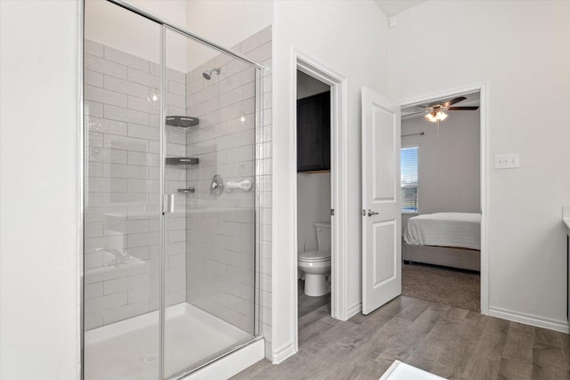 bathroom featuring a stall shower, baseboards, toilet, and wood finished floors