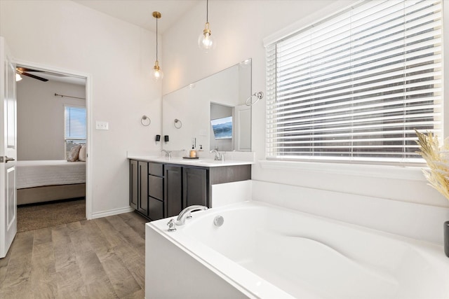 ensuite bathroom with ensuite bath, a garden tub, wood finished floors, and a healthy amount of sunlight