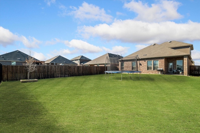 view of yard with a trampoline and a fenced backyard