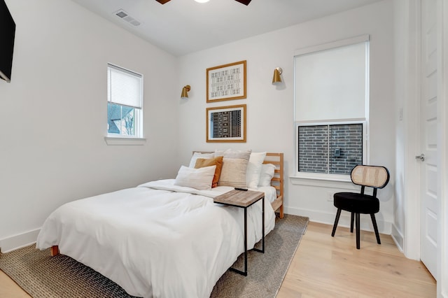 bedroom featuring light wood-style flooring, baseboards, visible vents, and ceiling fan