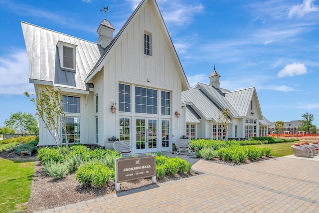 back of property featuring board and batten siding, french doors, a chimney, metal roof, and a standing seam roof