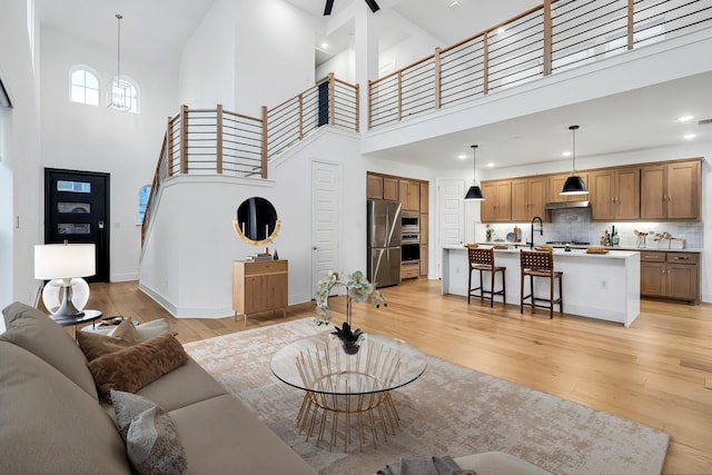 living area featuring recessed lighting, light wood-type flooring, baseboards, and a towering ceiling