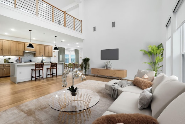 living room featuring recessed lighting, light wood-type flooring, a high ceiling, and visible vents