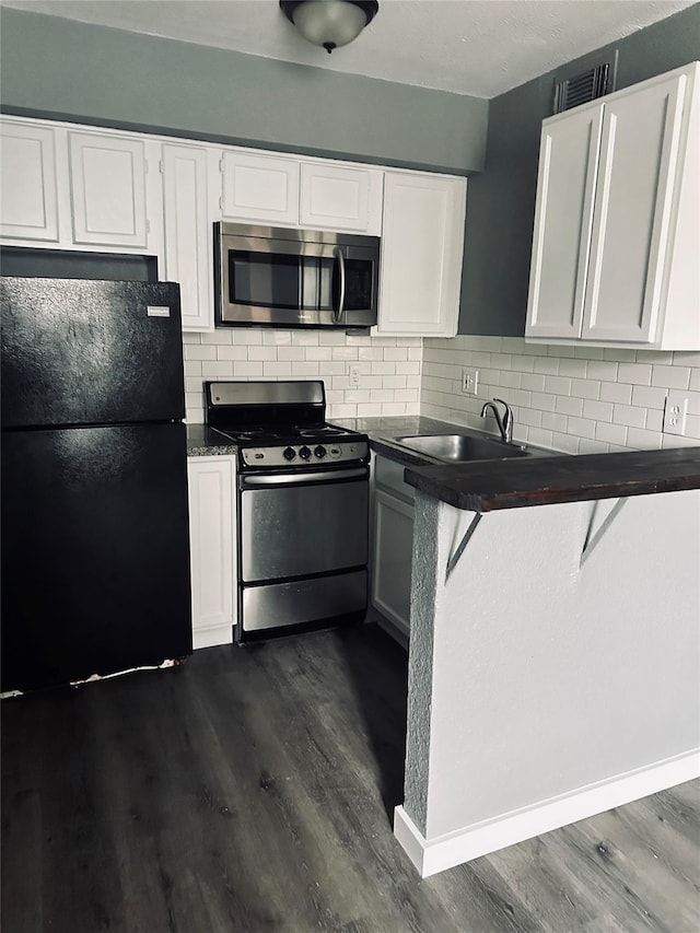 kitchen with dark countertops, freestanding refrigerator, a sink, gas range, and stainless steel microwave