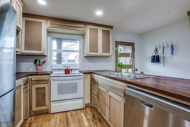 kitchen with butcher block countertops, a sink, recessed lighting, stainless steel appliances, and light wood finished floors