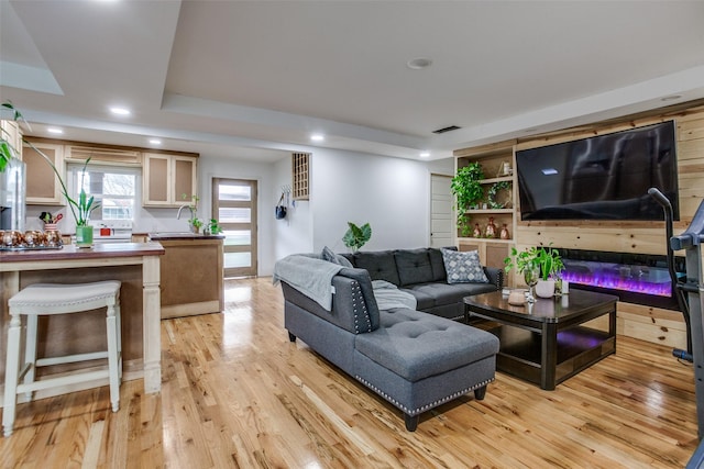 living room featuring recessed lighting, visible vents, light wood-style floors, and a tray ceiling