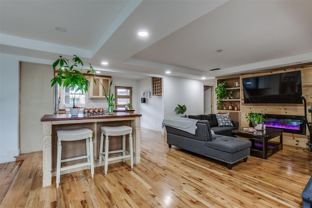 living area featuring recessed lighting, visible vents, a glass covered fireplace, and light wood-style flooring