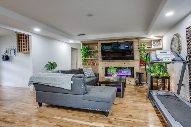 living area featuring a fireplace, recessed lighting, wood finished floors, and visible vents