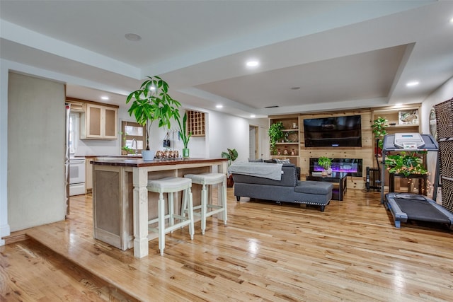 kitchen featuring a raised ceiling, a kitchen breakfast bar, light wood-style floors, and butcher block counters