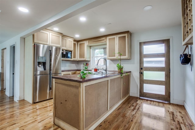 kitchen featuring light wood-style flooring, appliances with stainless steel finishes, a peninsula, and a sink