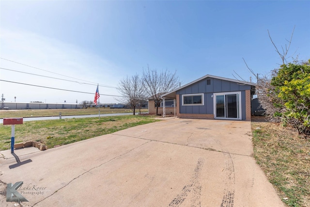 view of front of property with a front lawn, brick siding, and board and batten siding