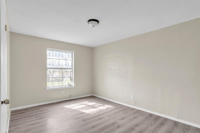 spare room featuring light wood finished floors and baseboards