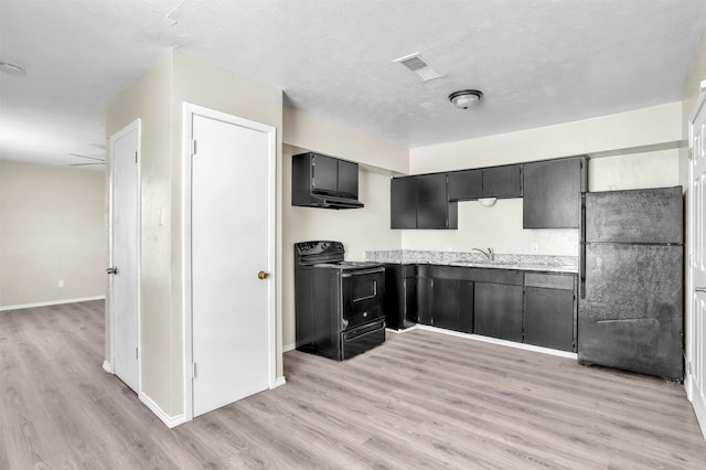 kitchen with visible vents, light wood-style flooring, freestanding refrigerator, range with electric cooktop, and light countertops