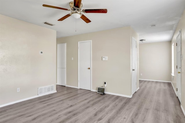 empty room with light wood-style floors, visible vents, and ceiling fan