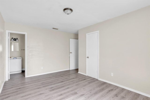 unfurnished bedroom featuring visible vents, light wood-style flooring, ensuite bath, and baseboards