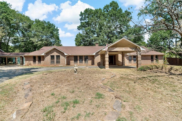 ranch-style house featuring brick siding and a chimney