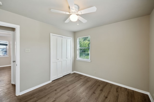 unfurnished bedroom with ceiling fan, a closet, baseboards, and wood finished floors