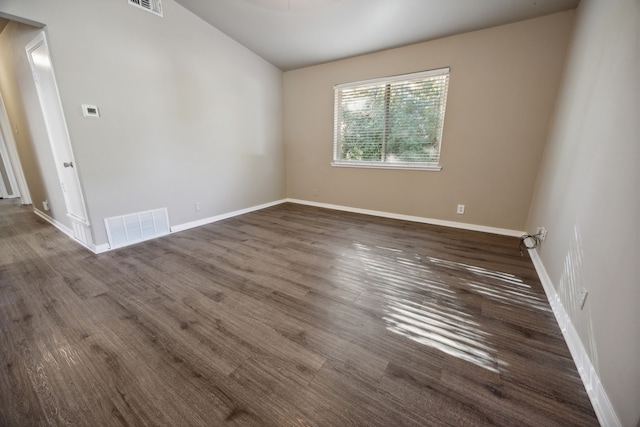 unfurnished room featuring arched walkways, visible vents, baseboards, and wood finished floors