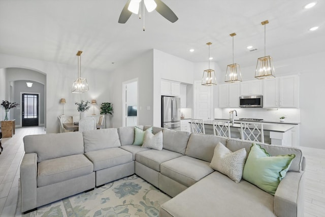 living room featuring visible vents, recessed lighting, arched walkways, ceiling fan, and light wood-style floors