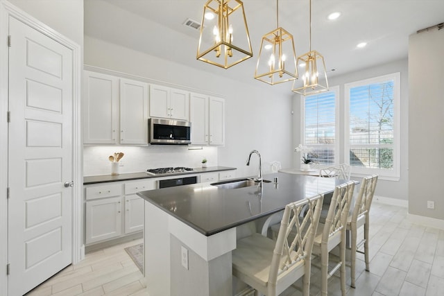 kitchen featuring a sink, backsplash, dark countertops, and appliances with stainless steel finishes