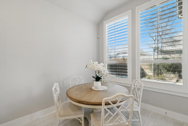 dining space featuring baseboards, plenty of natural light, and vaulted ceiling