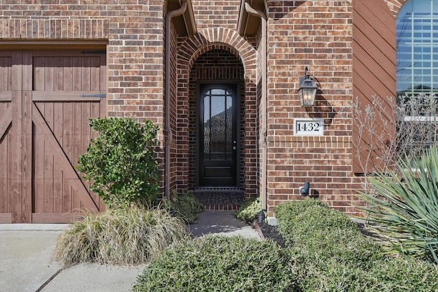 doorway to property featuring brick siding and a garage