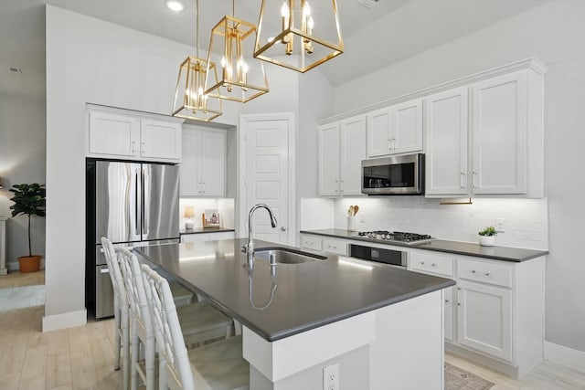 kitchen featuring dark countertops, decorative backsplash, appliances with stainless steel finishes, and a sink