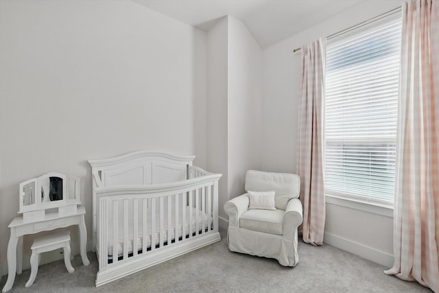 bedroom with baseboards, multiple windows, a crib, and carpet