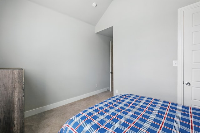 carpeted bedroom with vaulted ceiling and baseboards