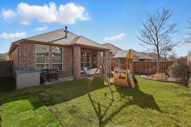 rear view of property featuring brick siding, a fenced backyard, a lawn, and a patio area