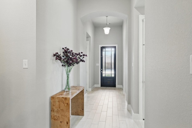 entryway featuring baseboards and arched walkways